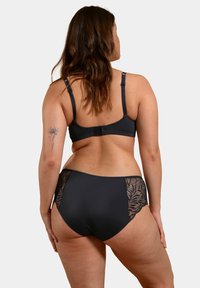 Ensemble soutien-gorge et culotte coordonné noir avec panneaux latéraux en dentelle, bretelles réglables et tissu doux pour le confort. Motif floral détaillé sur la dentelle.