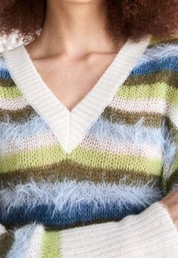 Jersey de cuello en V a rayas que presenta un hilo suave y texturizado en tonos verde, azul, blanco y marrón; diseño de punto suelto con detalles esponjosos.