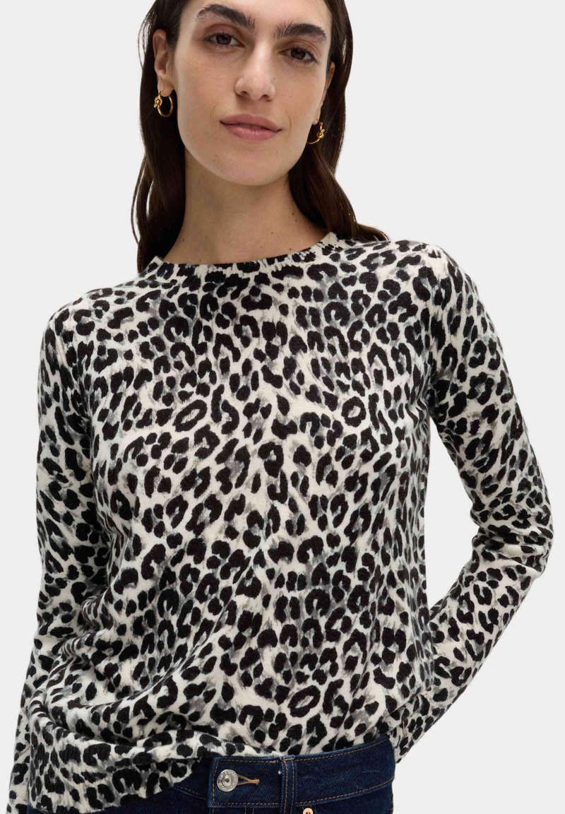 Leopardmönstrad tröja i svart och vitt, långärmad med rund halsringning, tillverkad av ett mjukt, texturerat tyg.