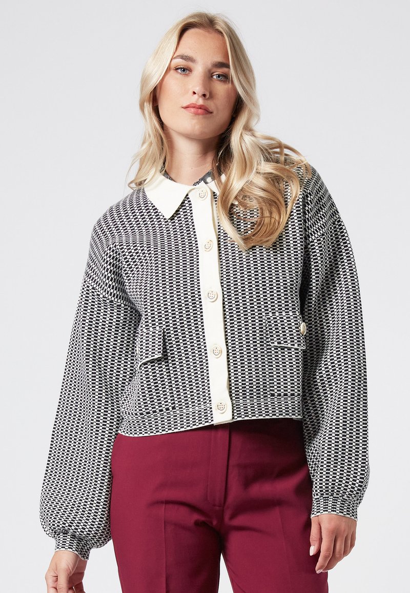 Rutigt svart och vitt kort jacka med vit krage, oversized ärmar, knäppning framtill och fickor. Lämplig för avslappnad användning.