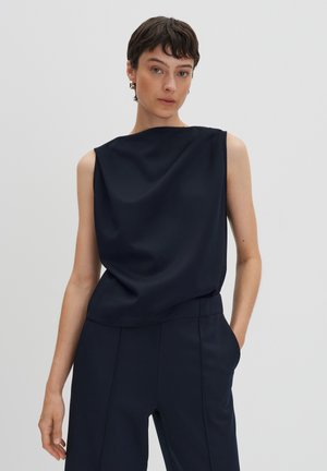 Marineblaue ärmellose Bluse mit lockerer Passform, glatter Textur, runder Ausschnitt und subtilen Drapierungen. Kombiniert mit passenden, maßgeschneiderten Hosen.