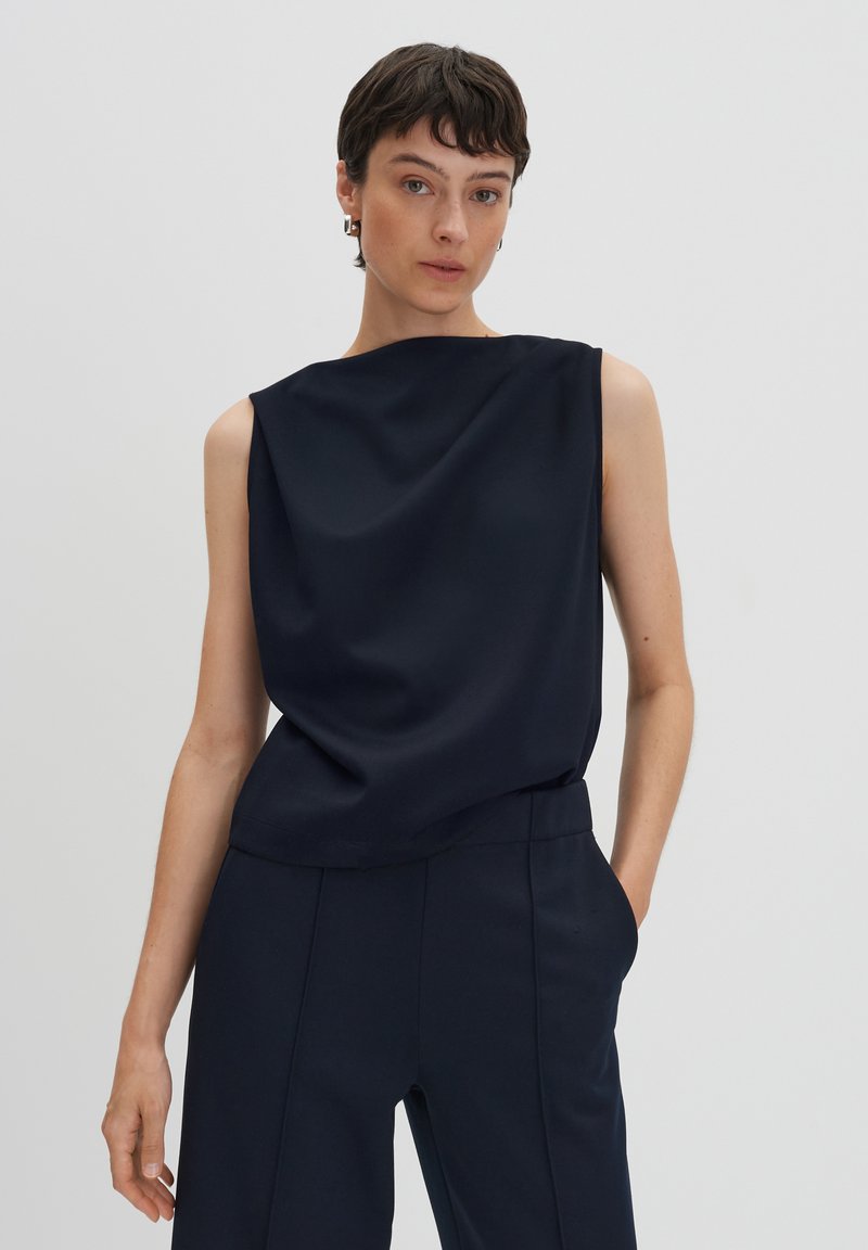 Navy sleeveless top with a relaxed fit, smooth texture, round neckline, and subtle draping. Paired with matching tailored trousers.