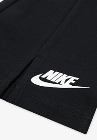 Svarte trening-shorts laget av bomullsblanding, med en hvit Nike-logo på kanten, teksturert stoff og rene sømmer.