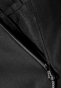 Czarne zamki posiadają kontrastujący biały uchwyt, otoczony gładkim, matowym materiałem. Szwy są wzmocnione wzdłuż zamka.