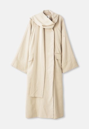 Robe beige au design fluide et aux manches larges. Fabriquée en tissu léger, elle dispose d'un grand col et de deux poches avant.