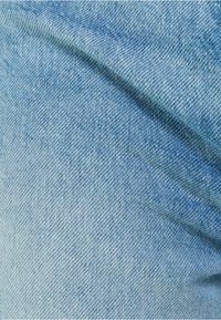 Ljust blå denimtyg med en synlig twillväv, som visar subtila texturvariationer och en slät yta. Inga tydliga mönster eller detaljer.