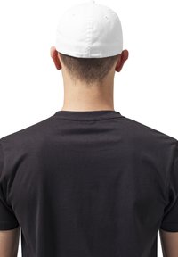 Sort T-shirt med korte ærmer og rund hals, set fra ryggen, parret med en hvid baseballkasket. Glat tekstur, afslappet design.