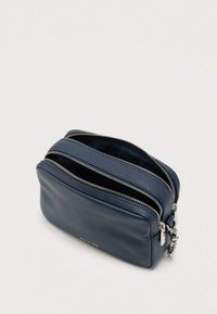 Tamnoplava kožna torbica s dva pretinca na patentni zatvarač, teksturiranom površinom, srebrnim ukrasnim elementima i zaobljenim pravokutnim oblikom.