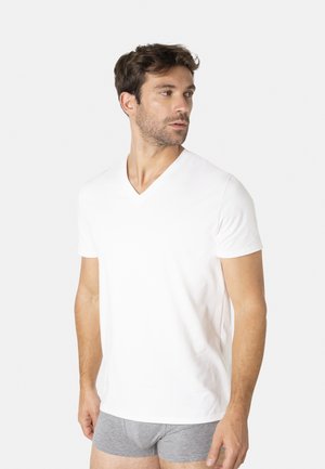 T-shirt blanc en coton à col en V avec manches courtes, porté avec un boxer gris. Texture lisse, coupe ajustée et apparence minimaliste.