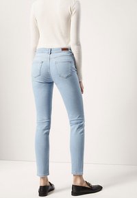 Ljusblåa skinny jeans i denim med midjehöjd, två bakfickor och en ren, enkel design. I kombination med svarta loafers.