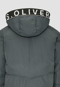 Graue Steppjacke mit einer strukturierten Oberfläche, ausgestattet mit einer abnehmbaren Kapuze und einem schwarzen Kragen mit weißer Schrift.