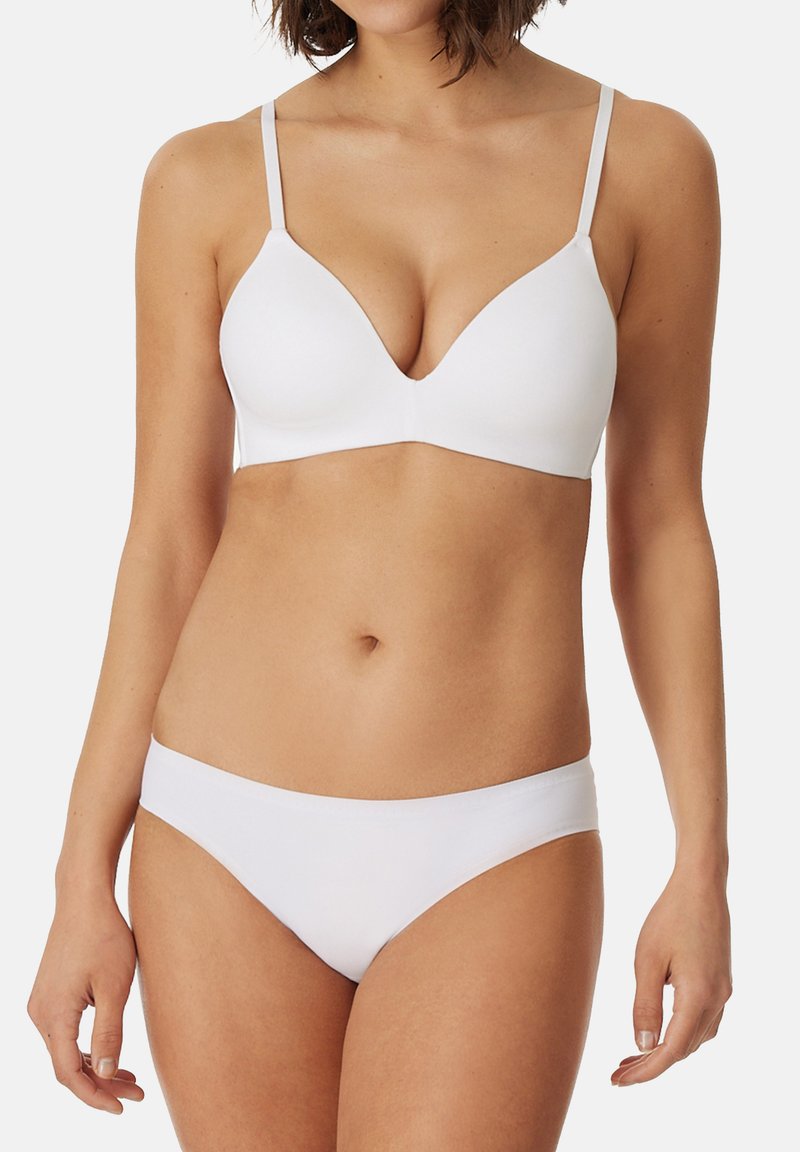 Bralette bianco e slip coordinati, entrambi realizzati in tessuto morbido. Il bralette presenta una scollatura profonda e spalline regolabili. Design minimale.