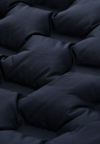 Tessuto imbottito blu navy con texture trapuntata caratterizzata da scomparti quadrati, con una finitura liscia e opaca e una sensazione morbida.