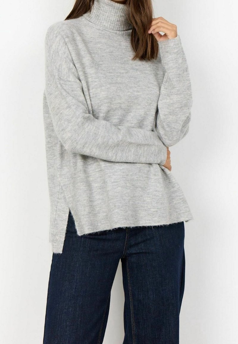 Pull à col roulé gris clair avec une coupe décontractée, fentes sur les côtés et poignets côtelés. Confectionné en tissu tricoté doux, avec un dos légèrement plus long.