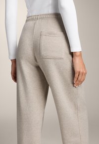 Beige, zachte sweatpants van stof met een elastische tailleband, voorzien van een enkele achterzak en een relaxte pasvorm. Soepele textuur en een op maat gemaakte uitstraling.