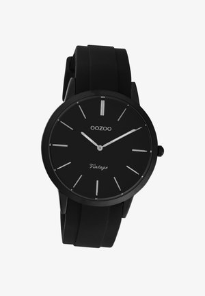 Montre noire avec un bracelet en silicone à finition mate, cadran rond simple, marqueurs d'heure et aiguilles argentés, avec la marque "OOZOO Vintage" sur le cadran.