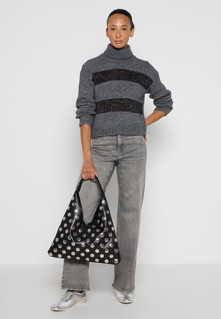 Maglione grigio lavorato a maglia con strisce nere glitterate, abbinato a jeans grigio chiaro e una grande borsa nera decorata con puntini metallici argentati.