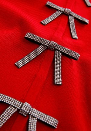 Red knit garment featuring three metallic rhinestone-encrusted bows, showcasing a smooth texture and a fitted design.