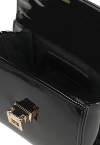 Schwarze Handtasche aus lackiertem Leder mit rechteckiger Form, glänzender Oberfläche und goldfarbener Verschluss. Das Innenfutter besteht aus weichem Stoff.
