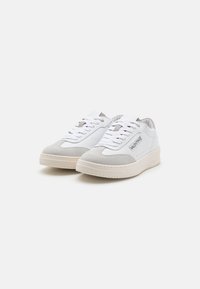 White and gray sneakers featuring a smooth leather upper and suede accents, with a rubber sole and lace-up design.