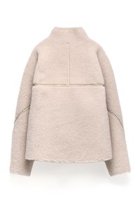 Beżowa polarowa kurtka z wysokim kołnierzem, długimi rękawami i widocznymi detalami szwów, pokazana z tyłu na białym tle.