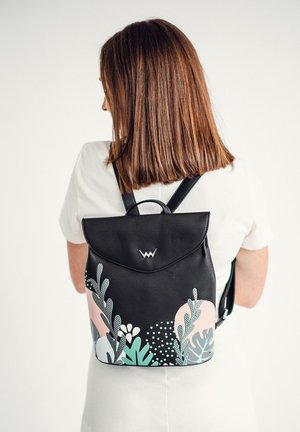 Černý kožený batoh s kulatým víkem, zdobený vícebarevnými květinovými vzory v pastelové růžové a zelené barvě, a stříbrnými kovovými detaily.