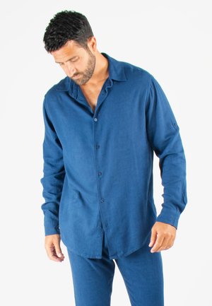 Chemise en lin bleu à manches longues avec une coupe décontractée, dotée d'un col évasé et de poignets boutonnés.