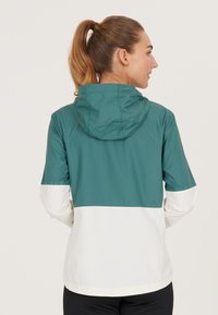 Waterdichte jas met een teal bovenstuk en een wit onderstuk, voorzien van een capuchon en elastische mouwen voor een goede pasvorm.