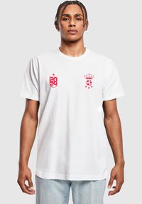 Hvid bomulds T-shirt med røde trykte grafikker: et skjold med "2024" og en krone over en fodbold på brystet. Korte ærmer.