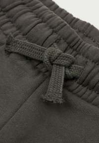 Dunkelgraue Sweatpants mit einem gewebten Kordelzug, ausgestattet mit einem strukturierten Bund und einer einfachen Knotendetail. Weicher Stoff mit einer glatten Oberfläche.