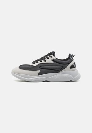 Schwarz-weißer Low-Top-Sneaker mit strukturiertem Obermaterial, dicker weißer Sohle, schwarzen Schnürsenkeln und Lasche an der Ferse mit Logodetail.