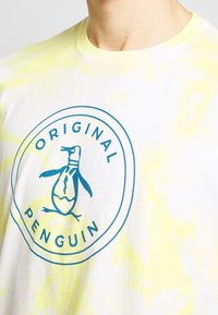 Bílá bavlněná tričko s krátkým rukávem se žlutým tie-dye vzorem, s modrým kruhovým logem tučňáka a textem "Original Penguin".