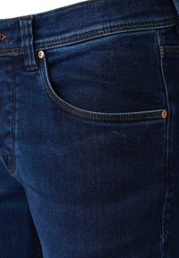 Dunkelblaue Jeans aus Denim mit glatter Textur und sichtbaren Nähten. Sie verfügen über ein klassisches Fünf-Taschen-Design und Kupferakzente.