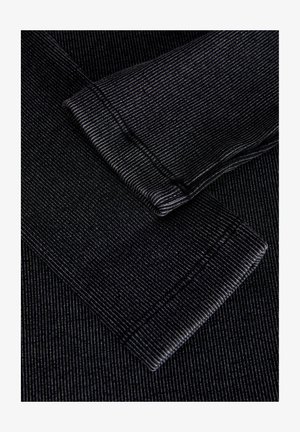 Mustra musta kangas kitsaste vertikaalsete triipudega. Näha on kaks rulli mansetti, mis toovad esile tekstuuri ja õmbluse detaile, luues kihilise efekti.