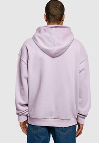 Felpa oversized viola chiaro con un grande cappuccio, spalle scese, polsini a coste e vestibilità comoda. Nessun logo visibile.