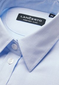 Jasnoniebieska, teksturowana koszula z długim rękawem, z kołnierzykiem w kształcie litery wskazującej, z metką "LANCERTO COMFORT PLUS" oraz plastikowym guzikiem.