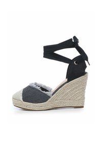 Wedge espadrille met een zwarte stoffen bovenkant en rafelige denim accenten. Voorzien van een geweven jute zool en verstelbare zwarte stoffen enkels verstelbanden.