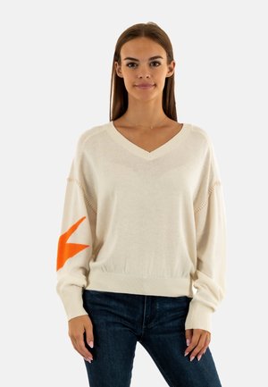 Maglione crema con scollatura a V e maniche lunghe e ampie; presenta un grande motivo a stella arancione sulla manica sinistra; tessuto morbido e strutturato.