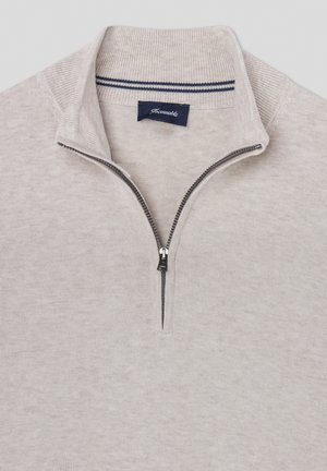 Felpa grigia chiara con zip realizzata in morbido tessuto. Presenta un colletto alto e una striscia blu marina decorativa all'altezza del collo. Chiusura con zip.