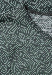 Materiál s vzorem, který zahrnuje geometrické linie v světle zelené barvě na tmavě šedém pozadí. Měkká textura s hladkým povrchem a kontrastním šitím.