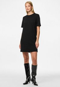 Vestido de camiseta negro brillante con un corte relajado, mangas cortas y escote redondo, combinado con botas altas hasta la rodilla en negro brillante.