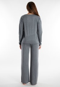 Graues Freizeitset bestehend aus einem langärmeligen Oberteil mit rundem Ausschnitt und weitem Bein mit gewelltem Saum. Weicher, strukturierter Stoff.