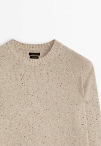 Vaaleanbeige neulepaita, jossa on pyöreä pääntie, pilkullinen kuviointi ja resorit hihoissa, valmistettu teksturoidusta langasta.