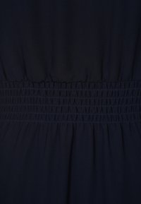 Tejido de vestido azul marino con cintura fruncida y smocking elástico. Textura suave con falda fluida y detalles de costura limpios.