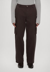 Ruskeat cargo-housut, jotka on tehty kestävästä kankaasta. Niissä on kaksi isoa sivutaskua, suora leikkaus ja vyötäröllä nappikiinnitys.