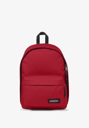 Zaino Eastpak rosso con una superficie liscia, dotato di una tasca frontale con zip e dettagli neri. Ha spallacci regolabili e una maniglia superiore.