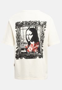 T-shirt en coton blanc présentant une impression en noir et blanc d'un portrait encadré avec un texte graffiti rouge, "Pas de cœur, pas d'art", au dos.