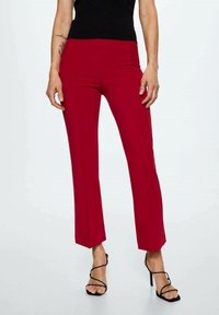 Rode op maat gemaakte broeken met een rechte pasvorm, een gladde textuur en minimale stikdetails. Gecombineerd met een zwarte top en zwarte sandalen met hoge hakken.