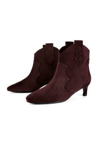 Bordowe zamszowe botki na kostkę z ostro zakończonym noskiem, ozdobnymi wirującymi wycinankami i 4 cm obcasem typu kitten heel. Posiadają uchwyty do łatwego zakładania.