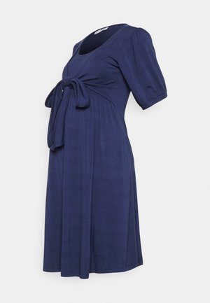 Vestido de maternidade azul-marinho em tecido suave, com decote arredondado, mangas curtas e bufantes, e um laço frontal para ajuste.